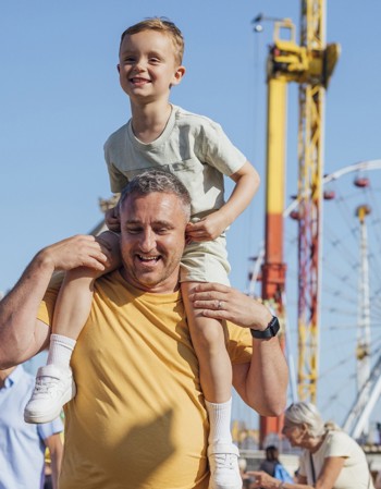 Father with his child on his shoulders walking in a fair ground